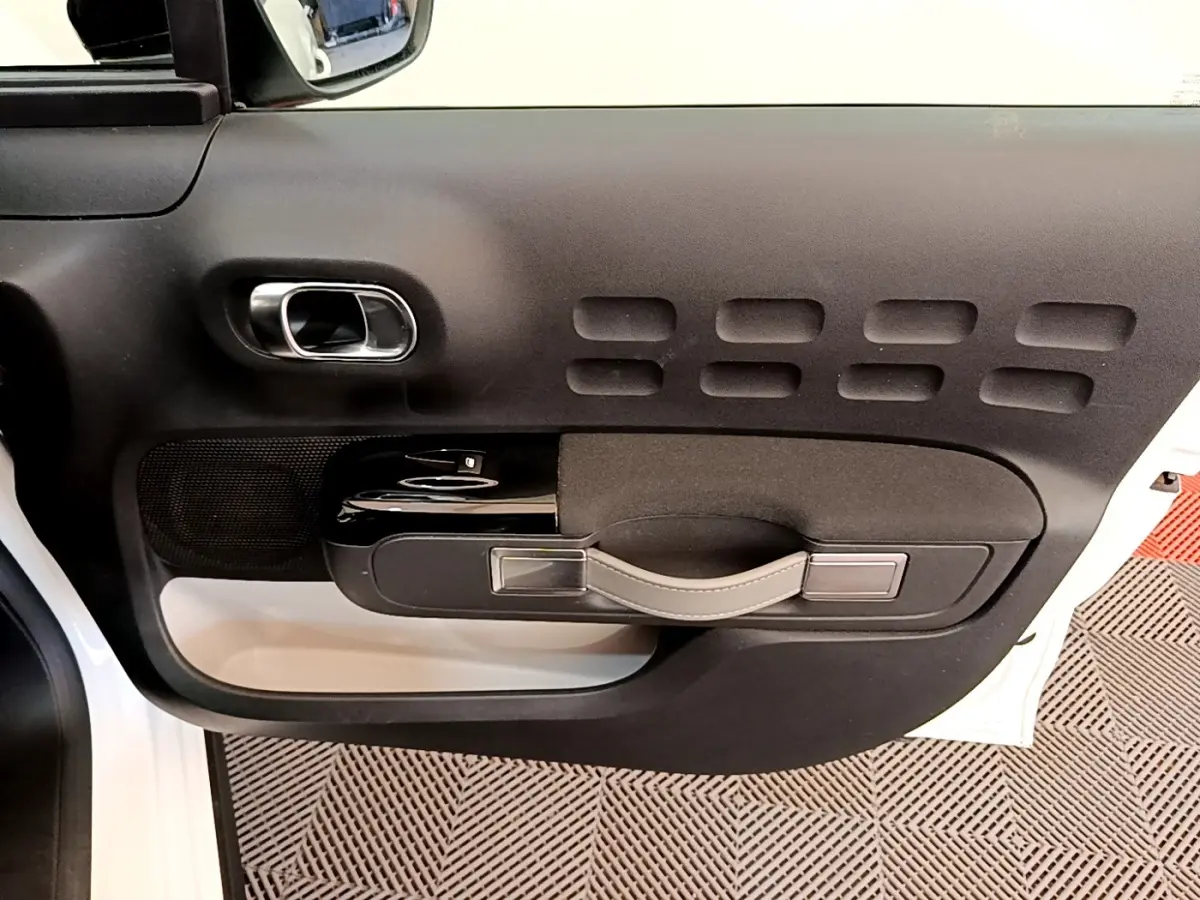 Vue intérieure de la porte avant gauche blanche d'une Citroën C3 2021 avec poignée noire et détails argentés.
