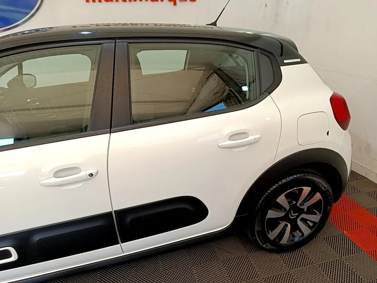 Vue côté droit arrière d'une Citroën C3 blanche avec protections noires et jantes alliage distinctives.
