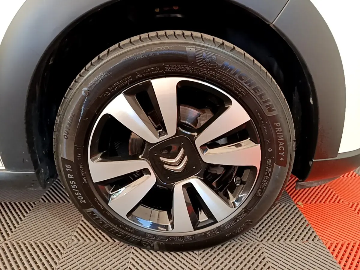 Gros plan sur la roue avant droite d'une Citroën C3 blanche, jante alliage bicolore avec logo Citroën central.