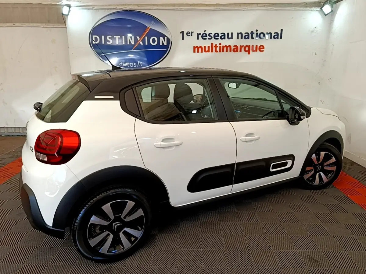 Citroën C3 blanche vue de profil droit, avec toit noir et protections latérales noires caractéristiques.
