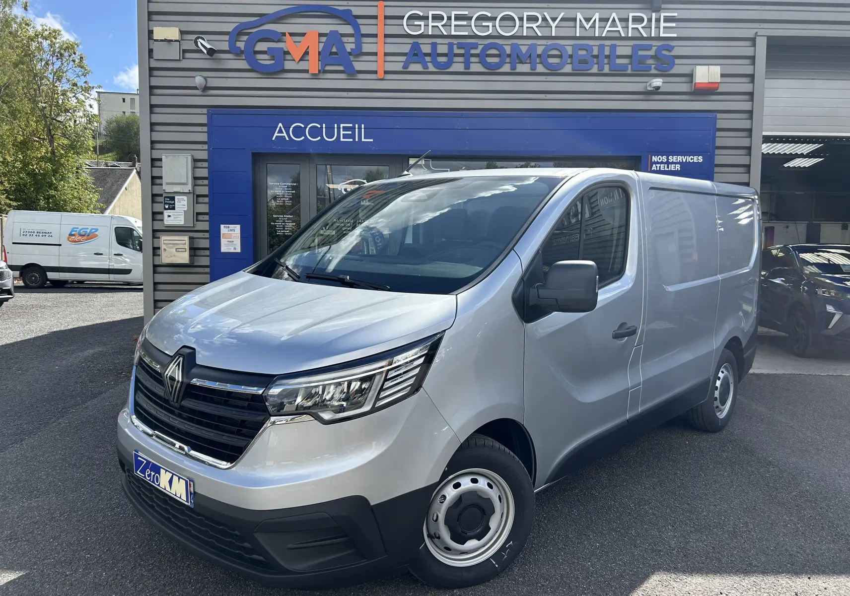 Renault Trafic Fourgon gris Highland vu en 3/4 avant droit devant un garage Gregory Marie Automobiles.