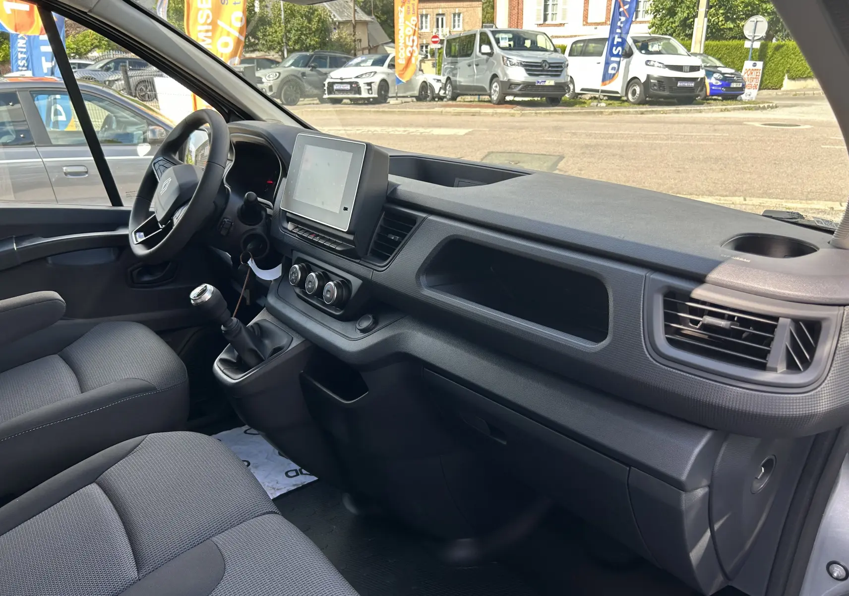 Intérieur du Renault Trafic Fourgon L1H1 2025, vue côté conducteur, tableau de bord moderne avec écran tactile et sièges gris.
