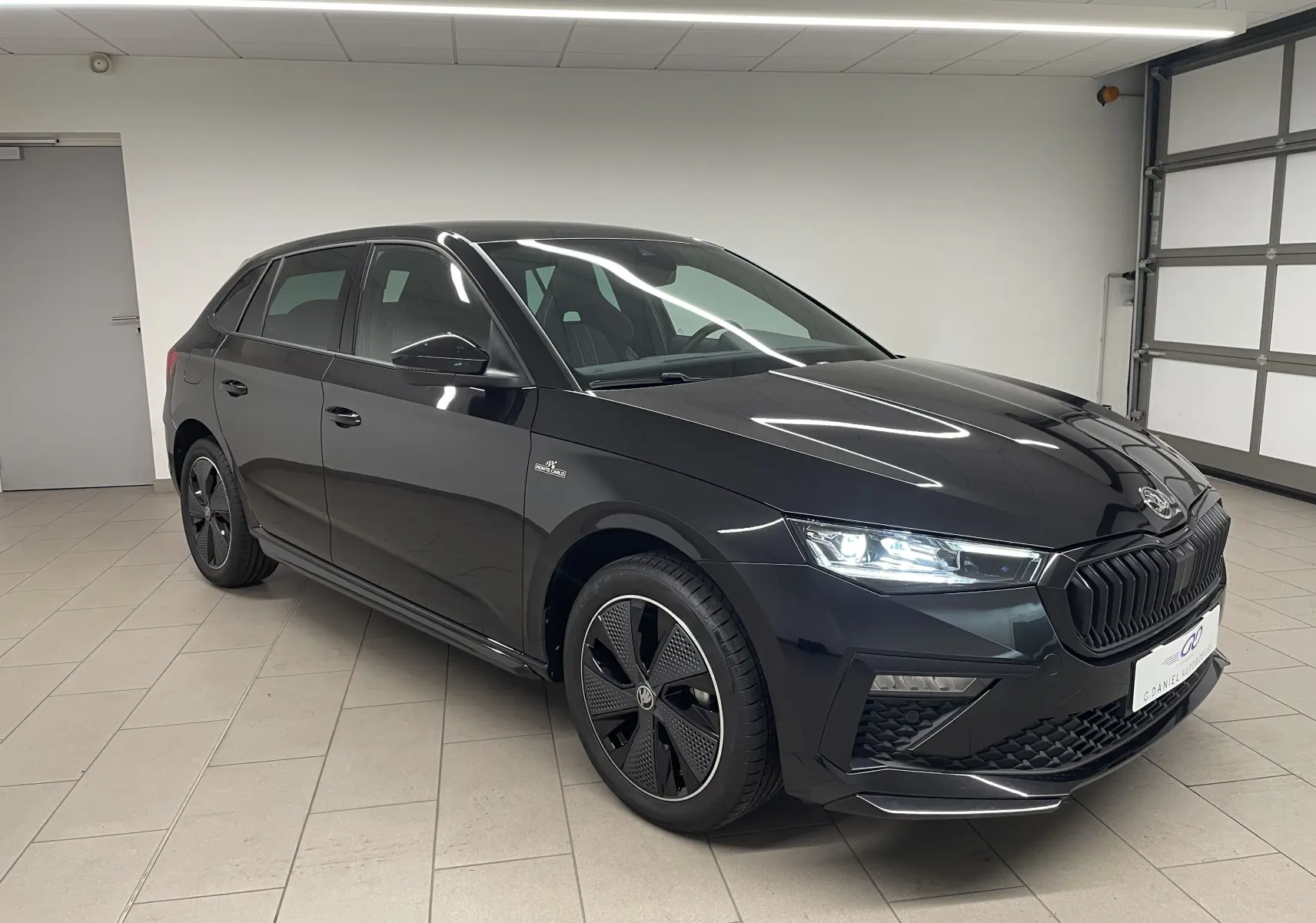 Vue 3/4 avant droite d'une Skoda Scala 1.5 TSI 150 DSG7 Monte-Carlo en noir Magic métallisé avec jantes distinctives.