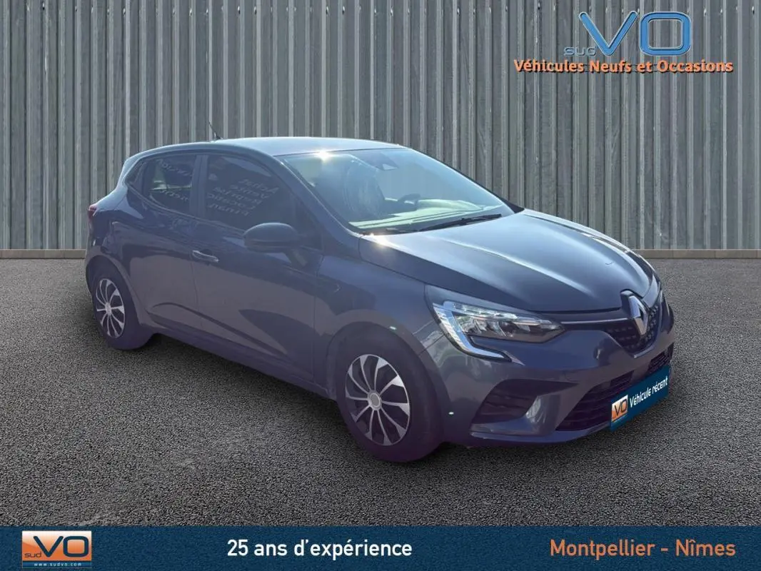 Renault Clio V TCe 90 gris vue 3/4 avant droit sur fond urbain avec jantes noires et grises.