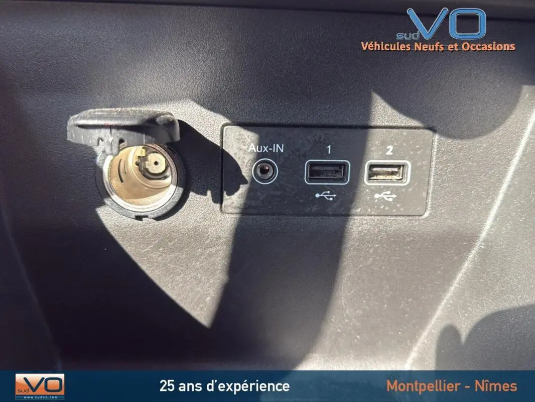 Prise allume-cigare et ports USB avec entrée Aux-IN sur tableau de bord noir d'une Renault Clio gris 2022.