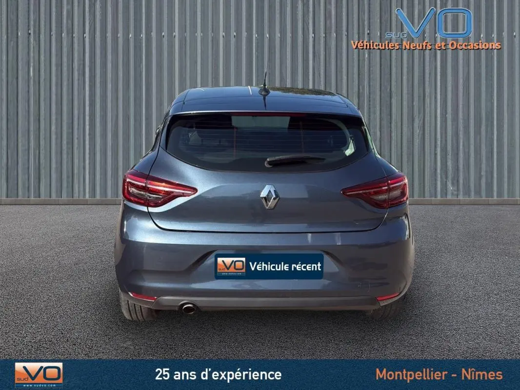 Vue arrière d'une Renault Clio gris métallisé 2022 avec feux LED et logo centré sur un fond industriel.