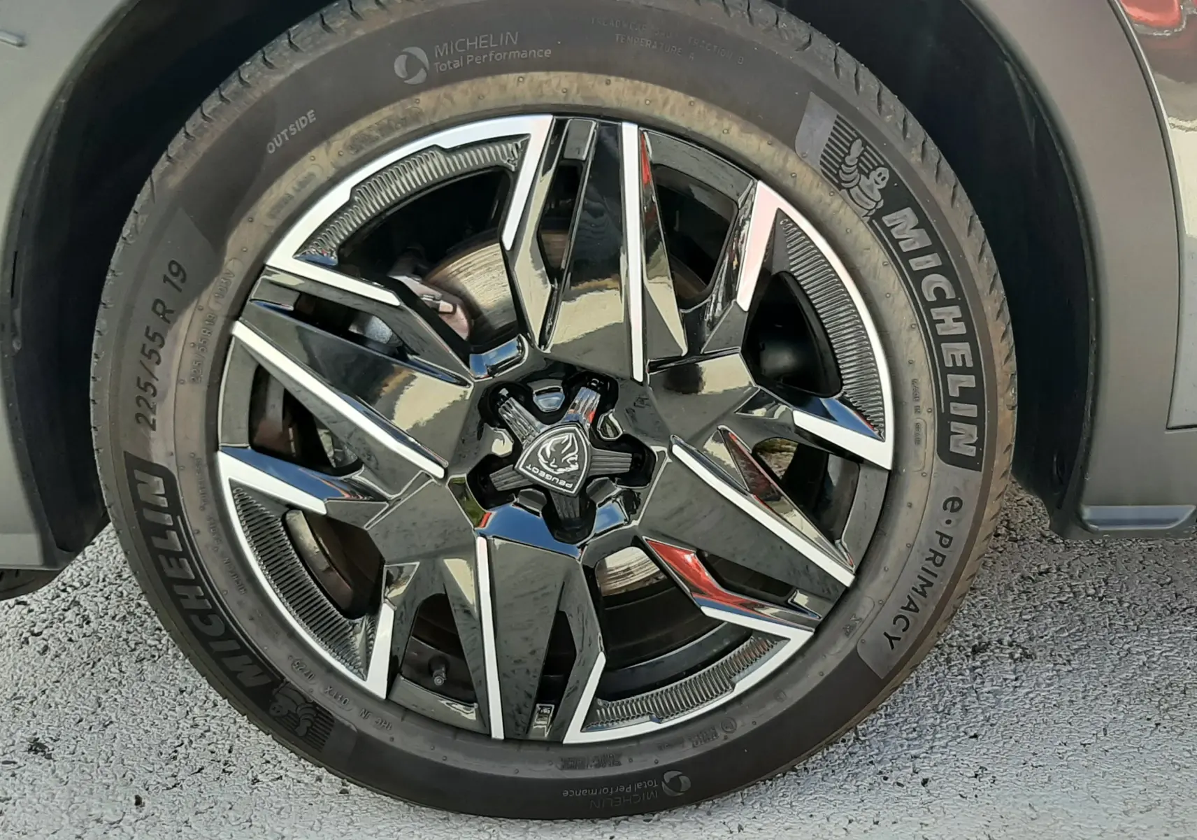Gros plan sur la roue avant droite du Peugeot 5008 Hybrid gris titane, avec jante alliage noire et argentée et pneu Michelin.