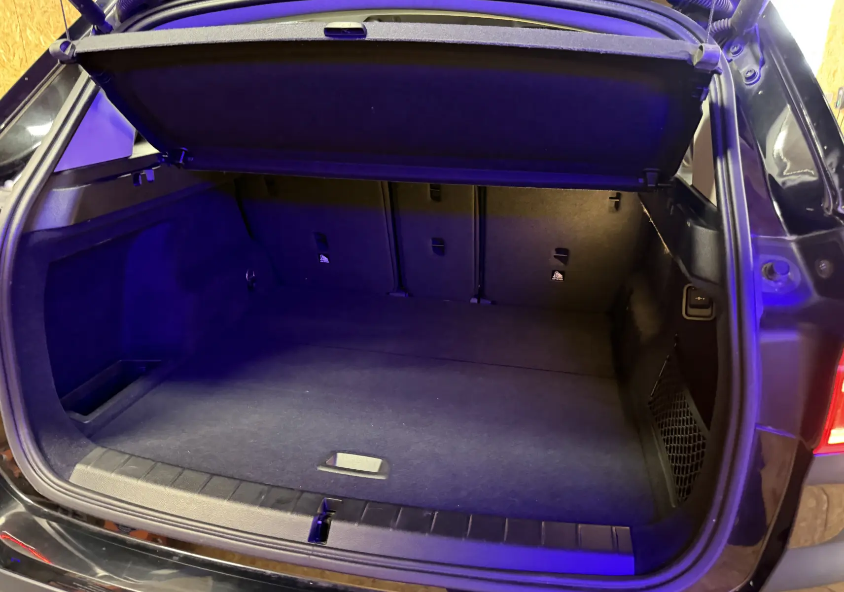 Coffre ouvert vu de l'arrière d'un BMW X1 noir (F48) avec cache-bagages et intérieur spacieux.