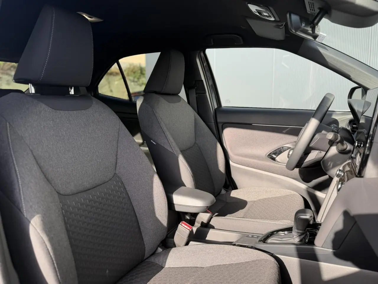 Vue intérieure côté droit des sièges avant gris clair et tableau de bord de la Toyota Yaris Cross 2026.