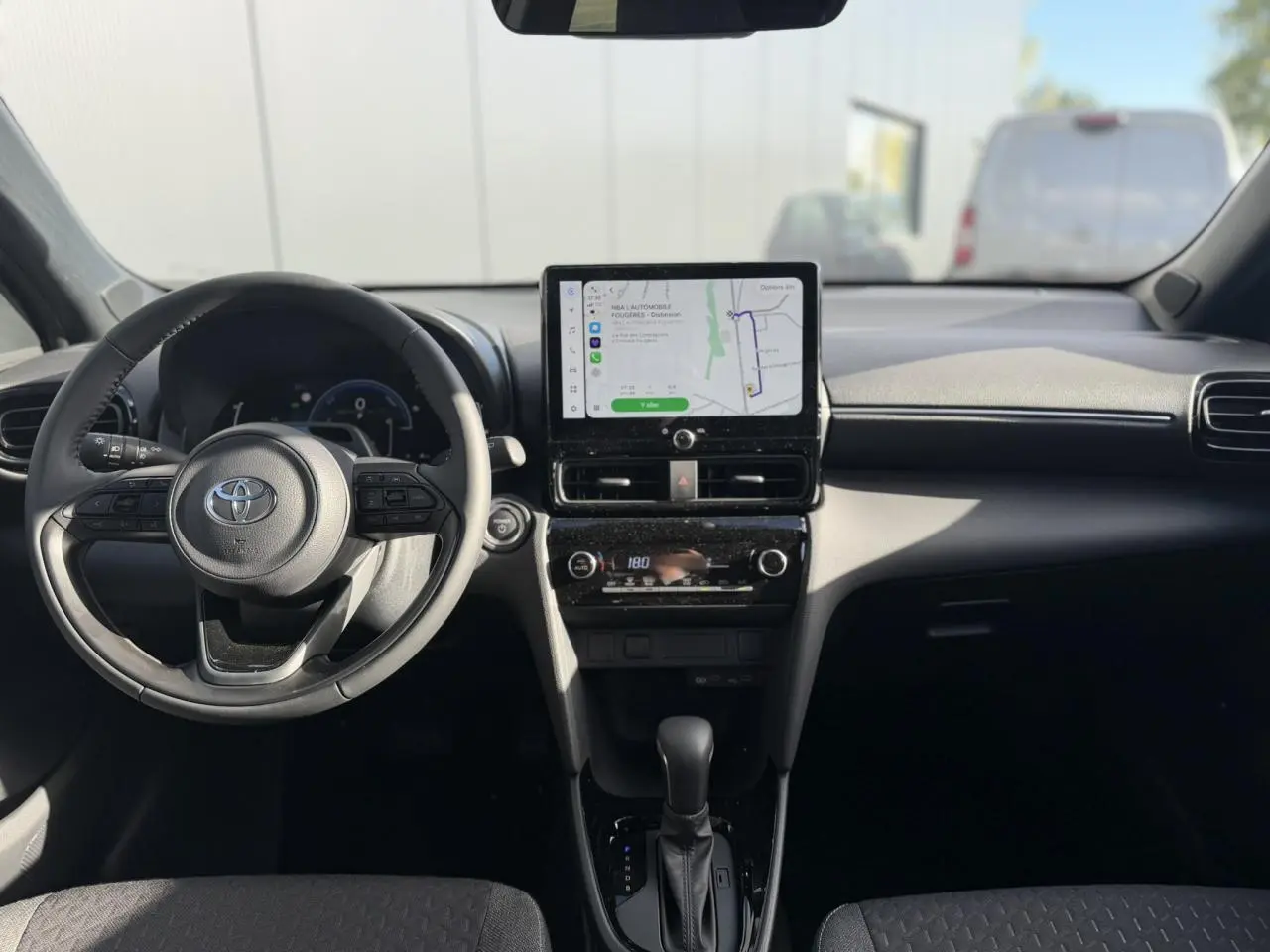 Vue intérieure avant de la Toyota Yaris Cross 1.5 Hybrid 130 BVA Design, tableau de bord noir avec écran tactile GPS et volant multifonctions.