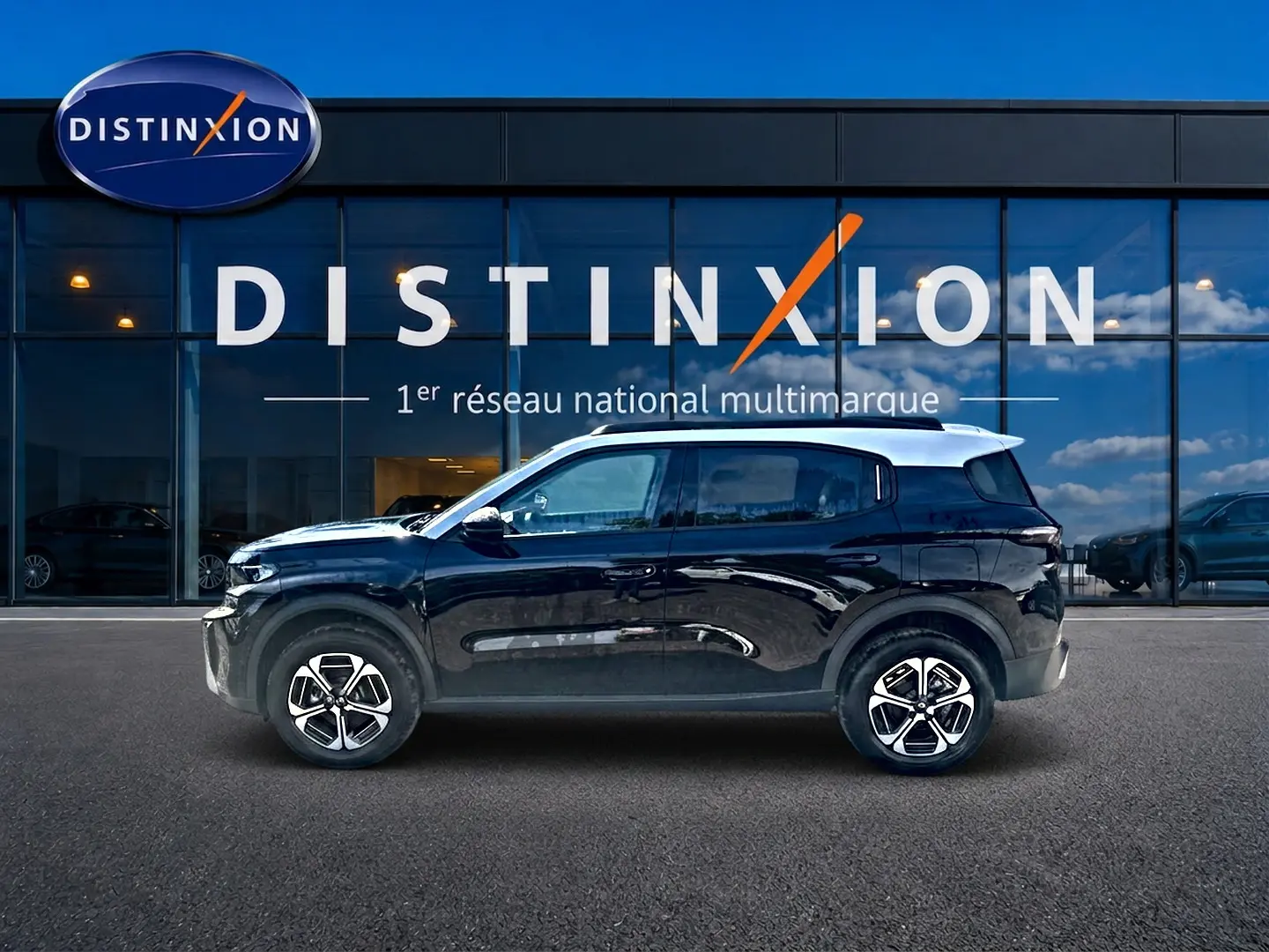 Profil latéral droit d'un Citroën C3 Aircross noir 2026 garé devant une vitrine avec logo Distinxion.