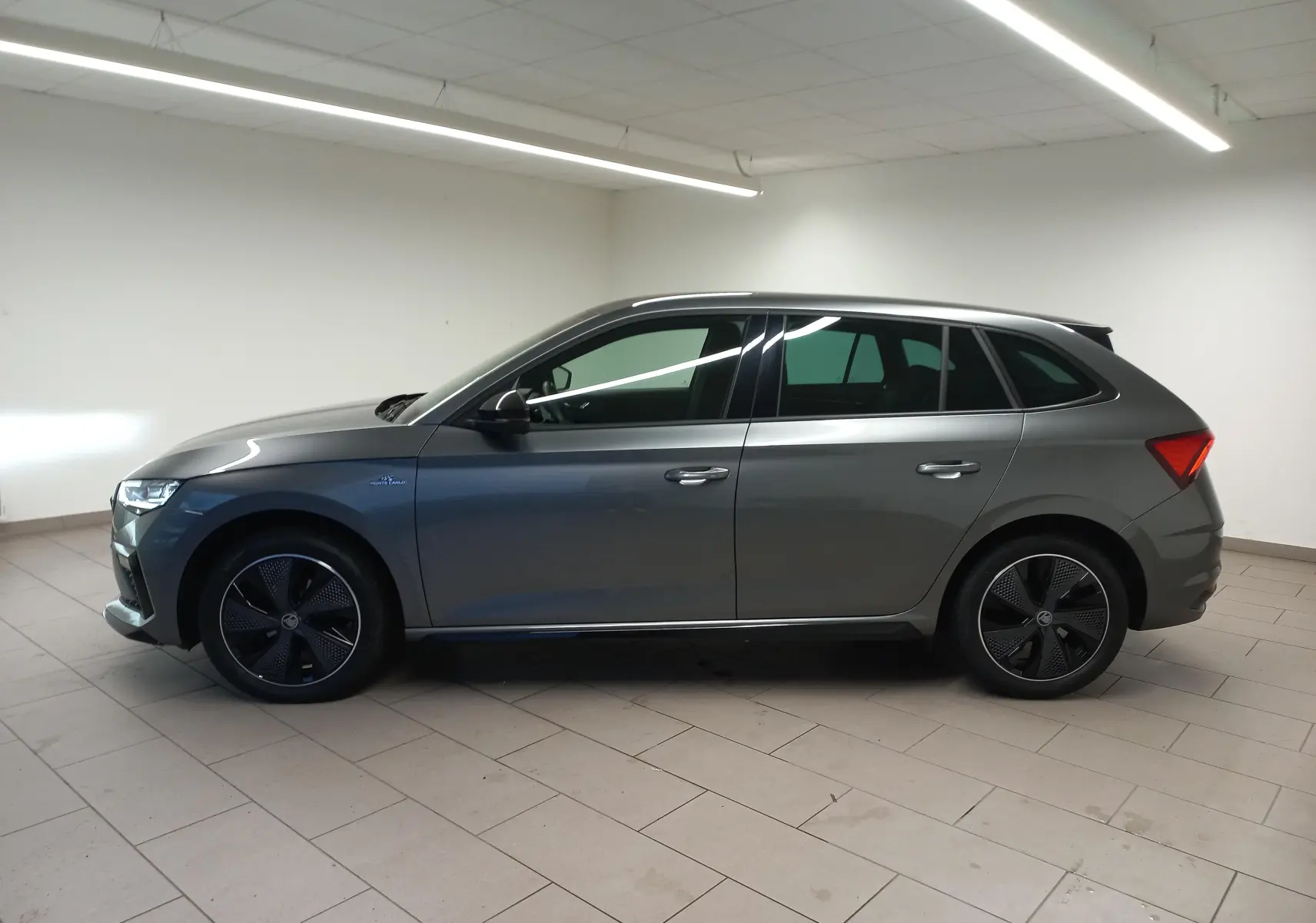 Profil droit d'une Skoda Scala 1.5 TSI 150 DSG7 Monte-Carlo en gris graphite métallisé, roues noires distinctives.