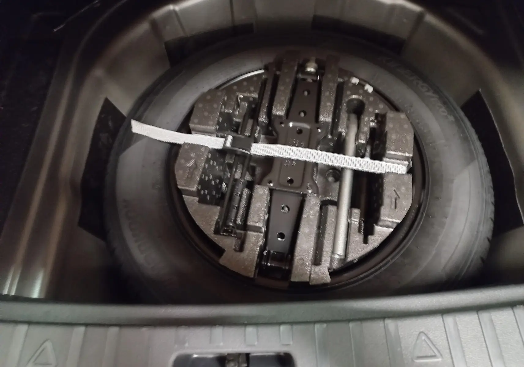 Gros plan sur la roue de secours et le double plancher du coffre du Skoda Scala 1.5 TSI 150 DSG7 Monte-Carlo gris graphite.