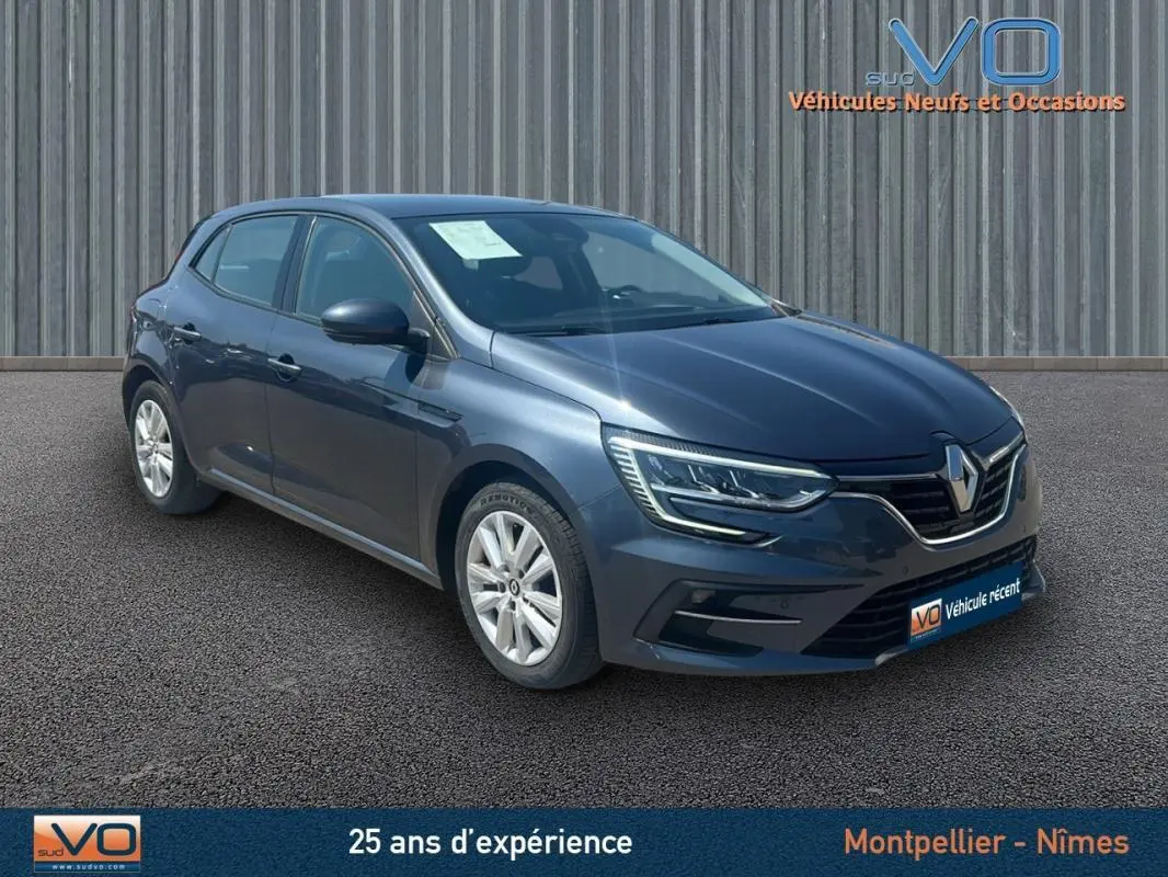 Renault Mégane IV Berline gris vue 3/4 avant droit, avec phares LED et jantes 16 pouces sur parking.
