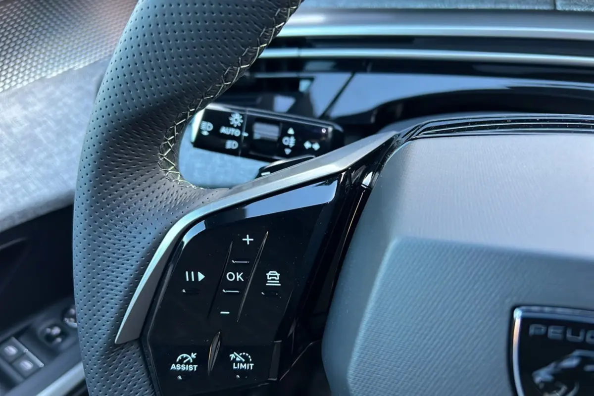 Gros plan sur le volant cuir perforé du Peugeot 3008 Hybrid 145 GT, avec commandes multifonctions noires brillantes.