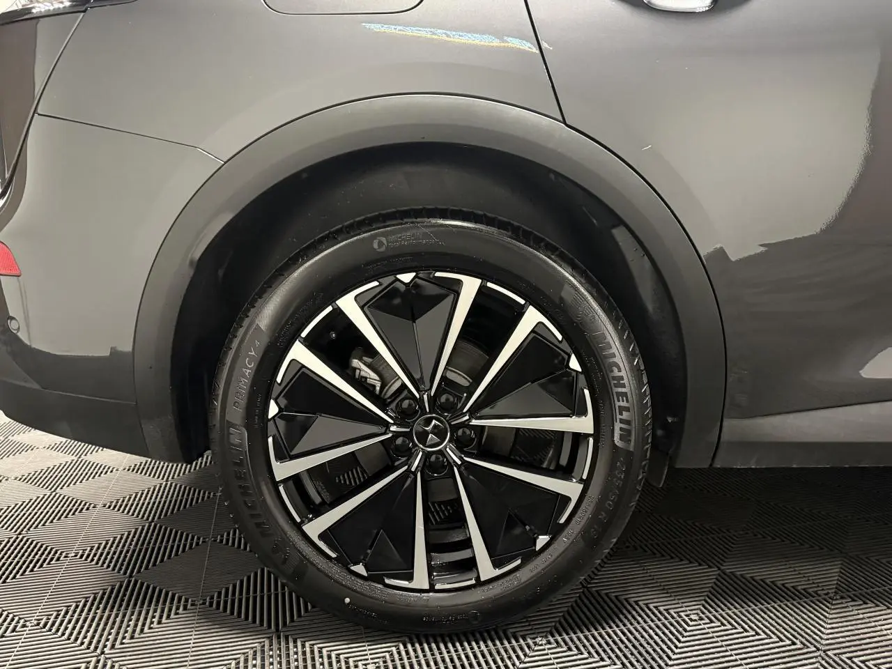 Gros plan sur la roue arrière droite d’un DS7 Crossback gris avec jante alliage noire et argentée au design géométrique.