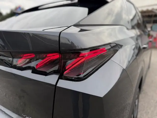 Gros plan sur le feu arrière droit rouge d’un Peugeot 3008 Hybrid 145 gris titane, soulignant ses lignes anguleuses.