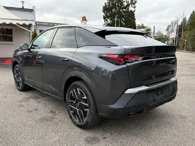 Vue 3/4 arrière droite d’un Peugeot 3008 Hybrid 145 GT gris titane avec jantes alliage bicolores et toit noir.