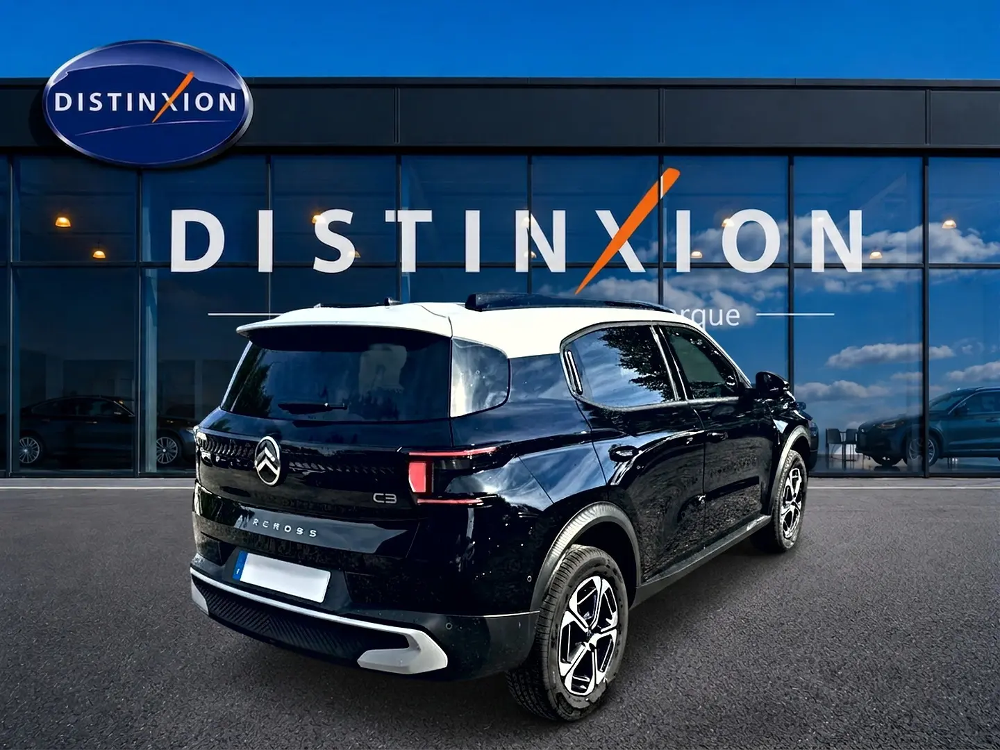 Vue 3/4 arrière droite d'une Citroën C3 Aircross 2026 noire avec toit blanc et jantes alu distinctives.