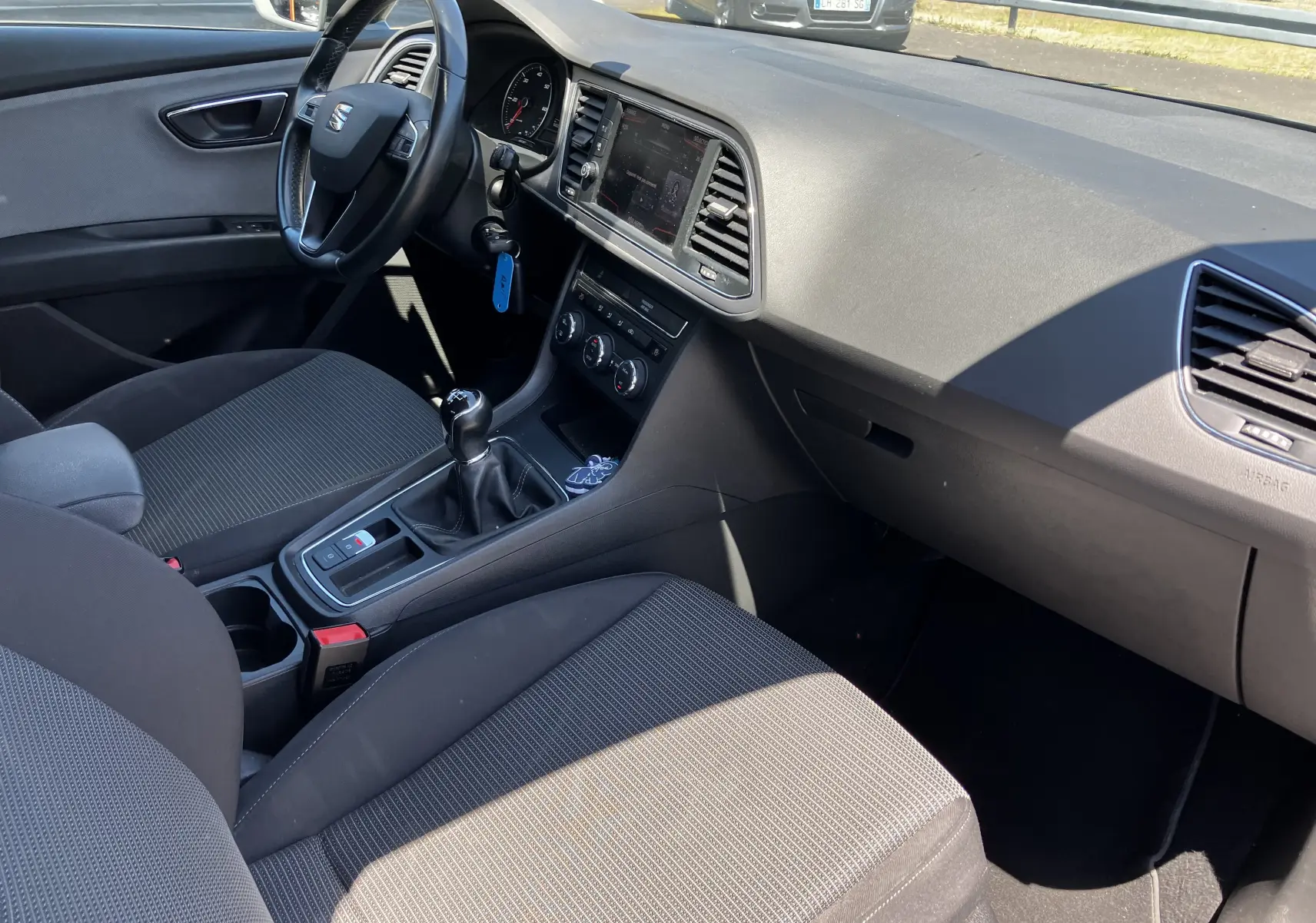 Intérieur noir de la SEAT LEON 1,6L TDI 115 STYLE 2018, vue côté conducteur sur tableau de bord et console centrale.