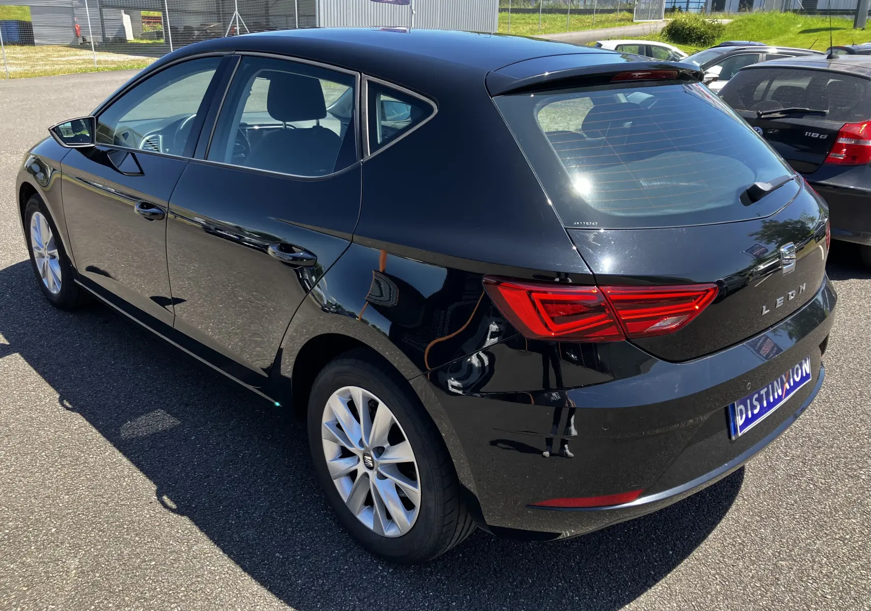 Vue 3/4 arrière droite d'une SEAT Leon noire 5 portes, soulignant ses feux arrière LED et jantes alliage.