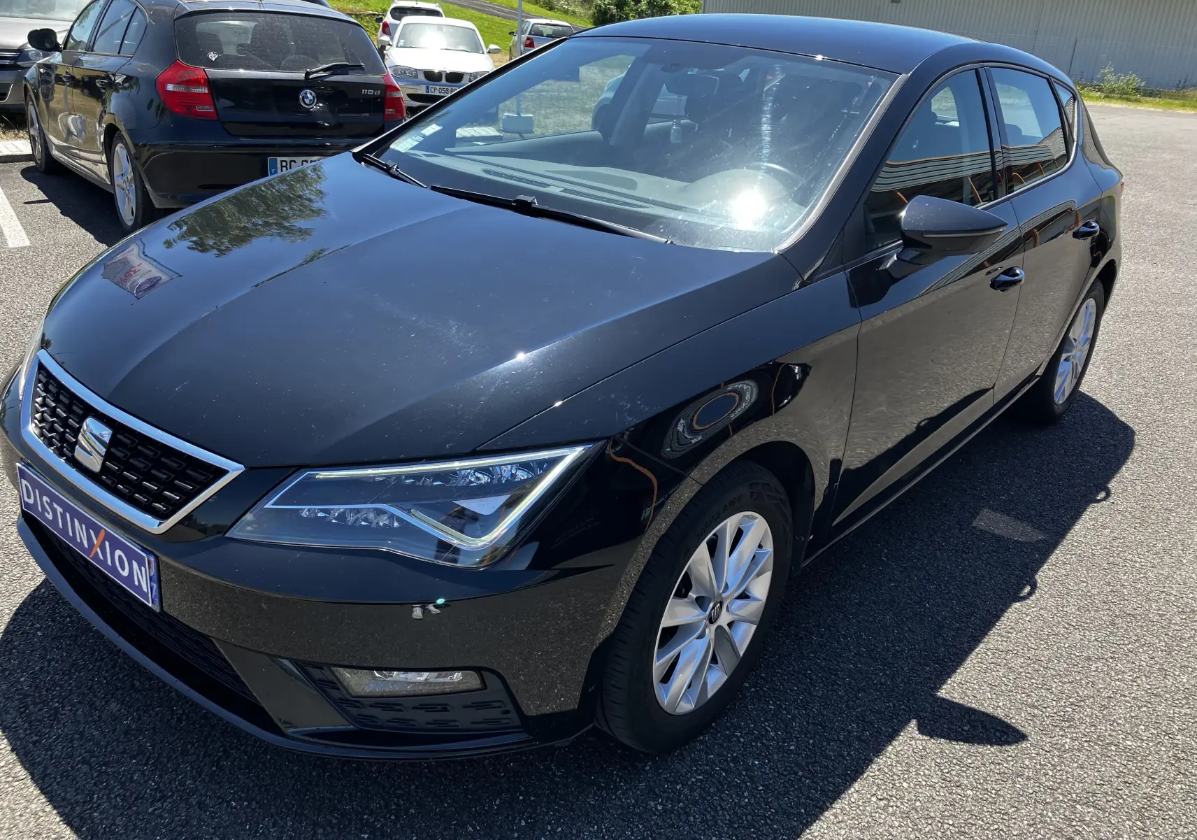 SEAT Leon 1,6L TDI 115 Style noir en 3/4 avant droit, avec jantes alliage et calandre chromée visible.