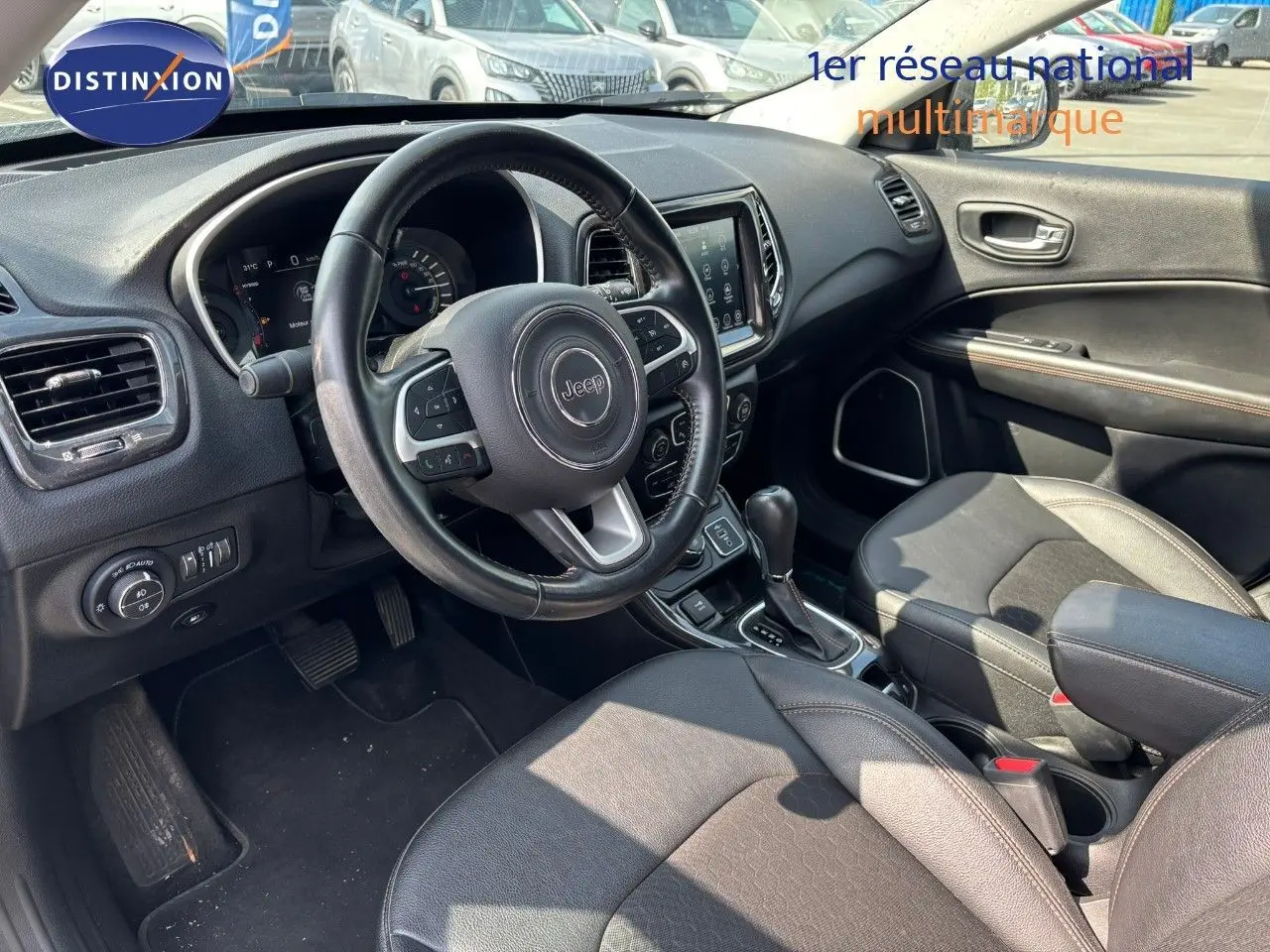 Intérieur du Jeep Compass 2021 hybride rechargeable, vue côté conducteur sur le tableau de bord et sièges en cuir noir.