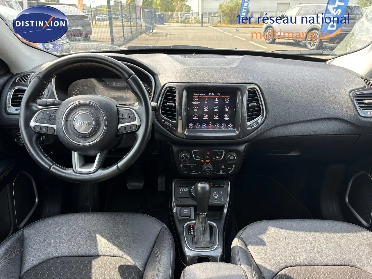 Vue intérieure avant du Jeep Compass hybride rechargeable 2021, tableau de bord et volant en cuir noir visibles.