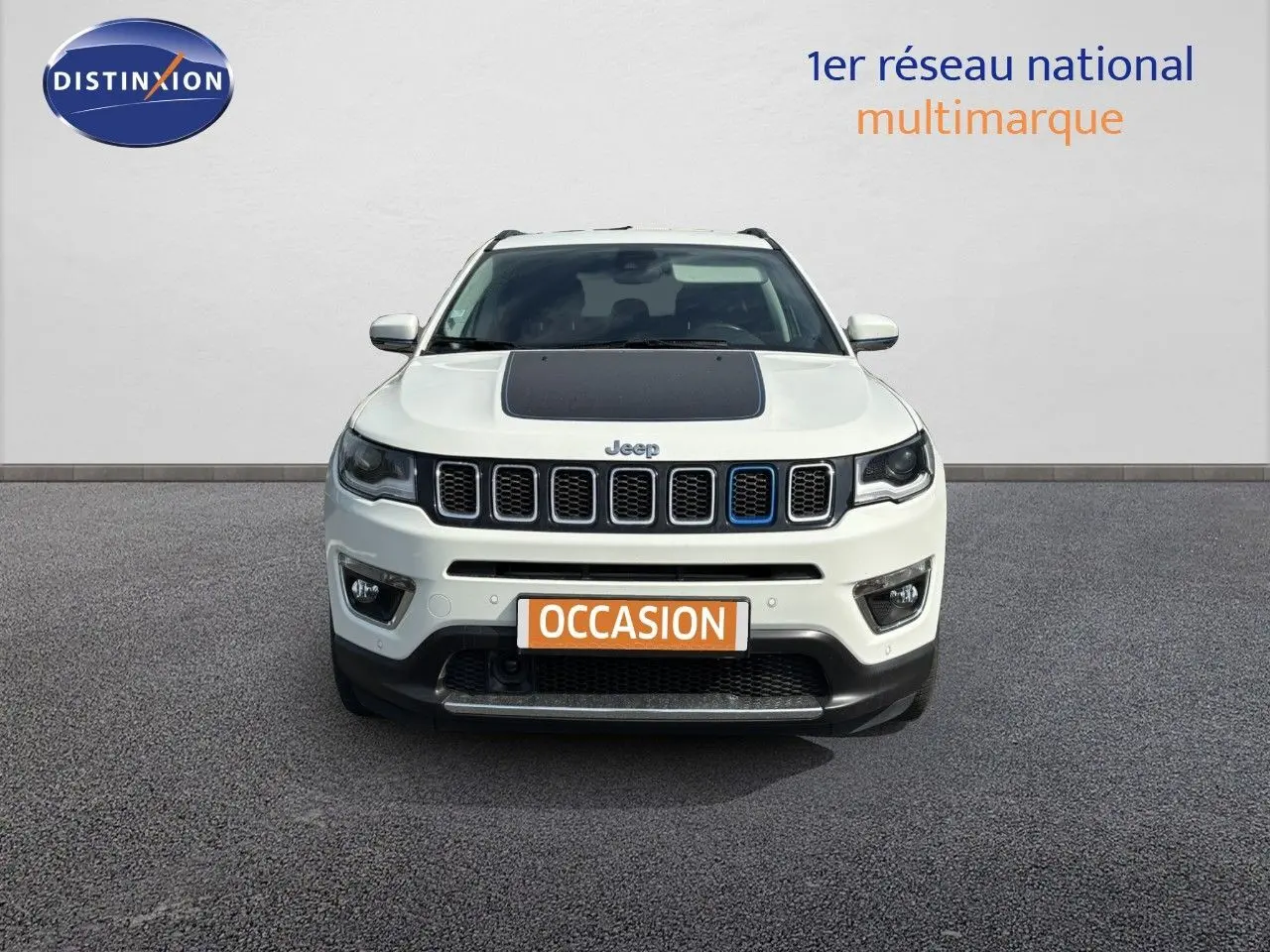 Vue frontale d'un Jeep Compass blanc avec capot noir et calandre caractéristique, en extérieur sur sol gris.