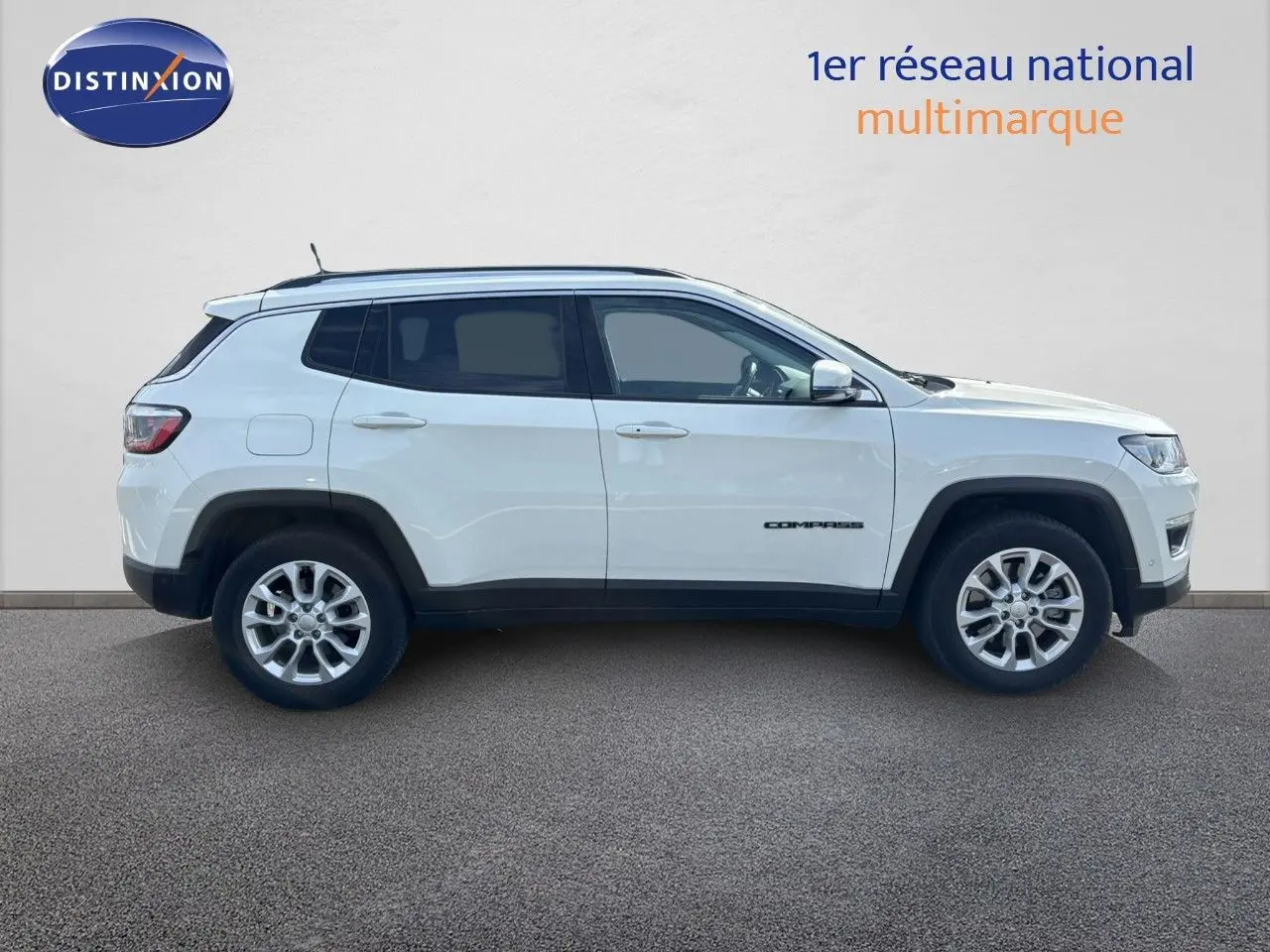 Profil côté droit d'un Jeep Compass blanc 2021 avec jantes alliage et détails noirs contrastants sur les passages de roue.