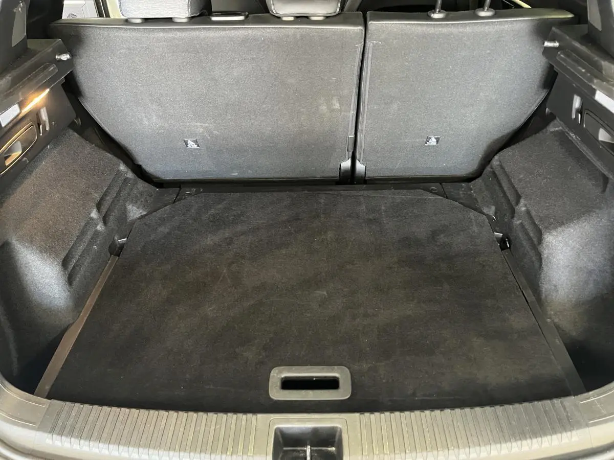 Coffre ouvert vu de l'arrière d'un Renault Austral 2024 blanc, montrant l'espace de chargement et banquette arrière rabattue.