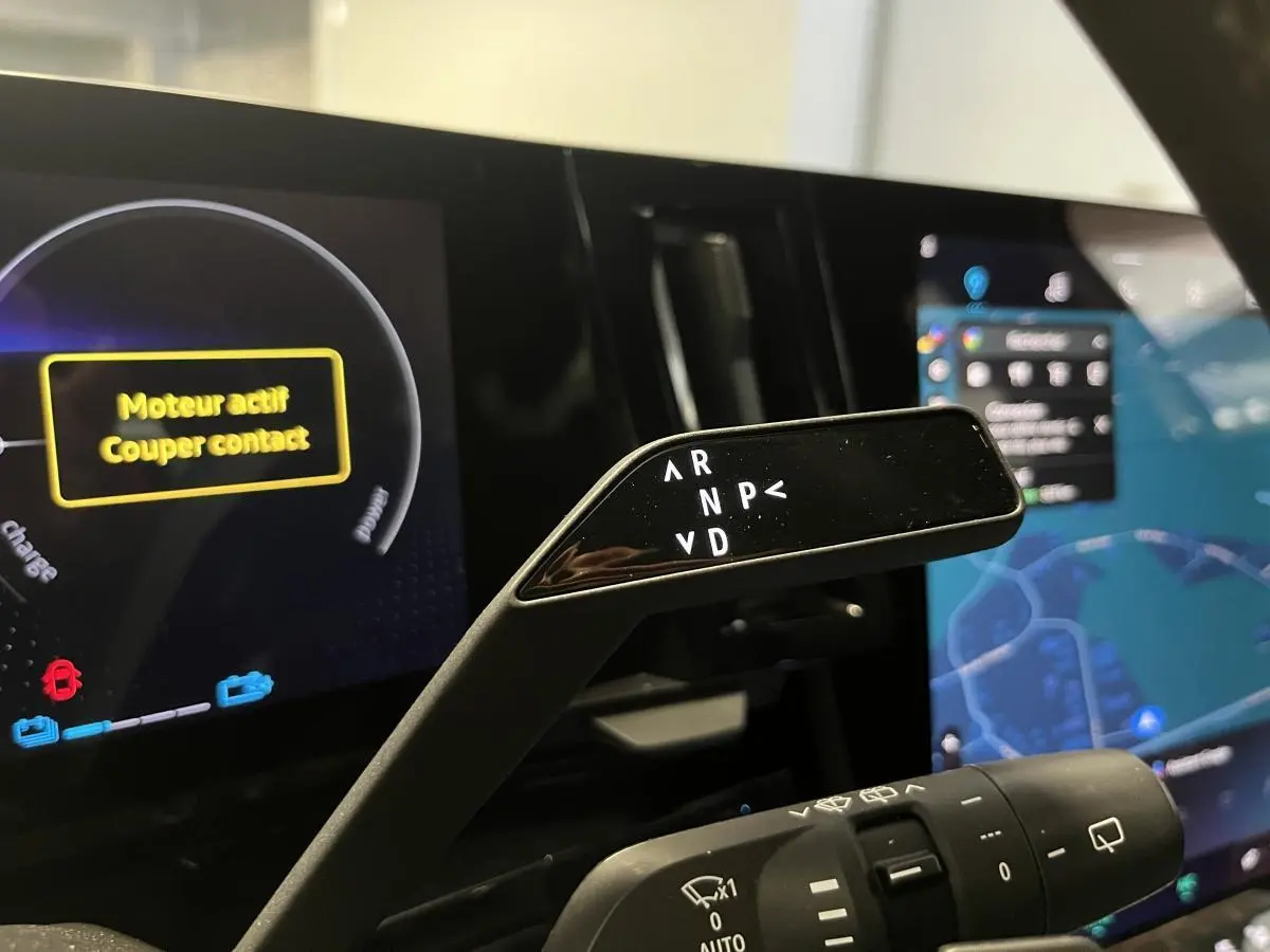 Gros plan sur la commande de boîte automatique dans l'habitacle du Renault Austral blanc, avec tableau de bord numérique en arrière-plan.