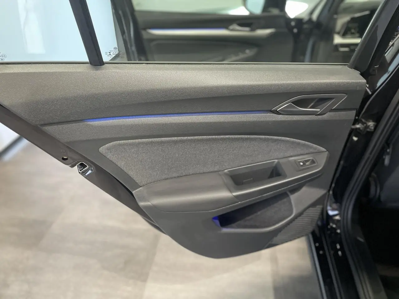 Porte arrière gauche noire de Volkswagen Golf 2024 avec éclairage d'ambiance bleu et garniture tissu et plastique.