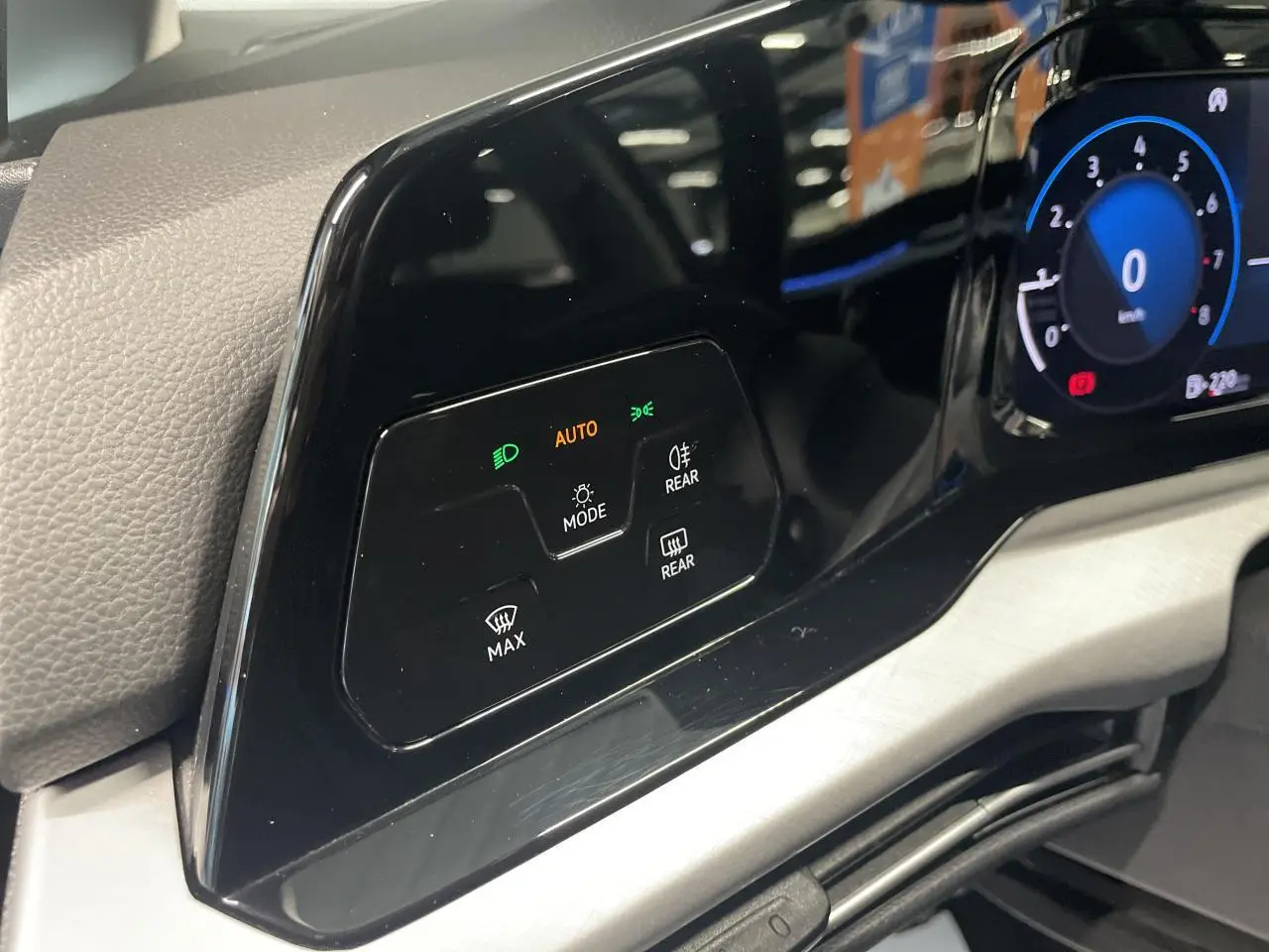 Détail du tableau de bord noir brillant de la Volkswagen Golf 2024 avec commandes d'éclairage et écran digital partiel.