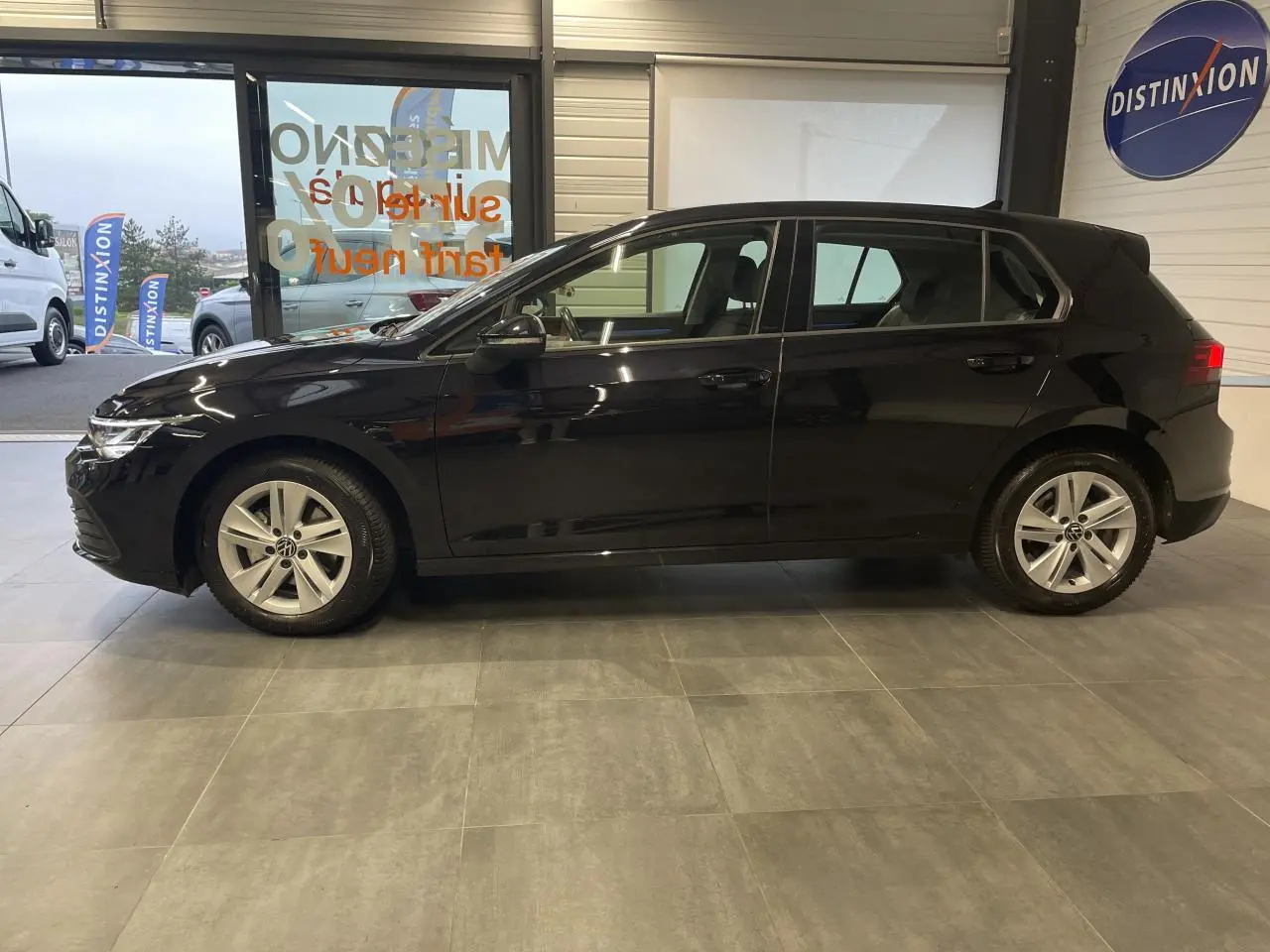 Profil côté gauche d'une Volkswagen Golf 1.5 eTSI Style noire, avec jantes alliage 17 pouces Nottingham, en intérieur showroom.