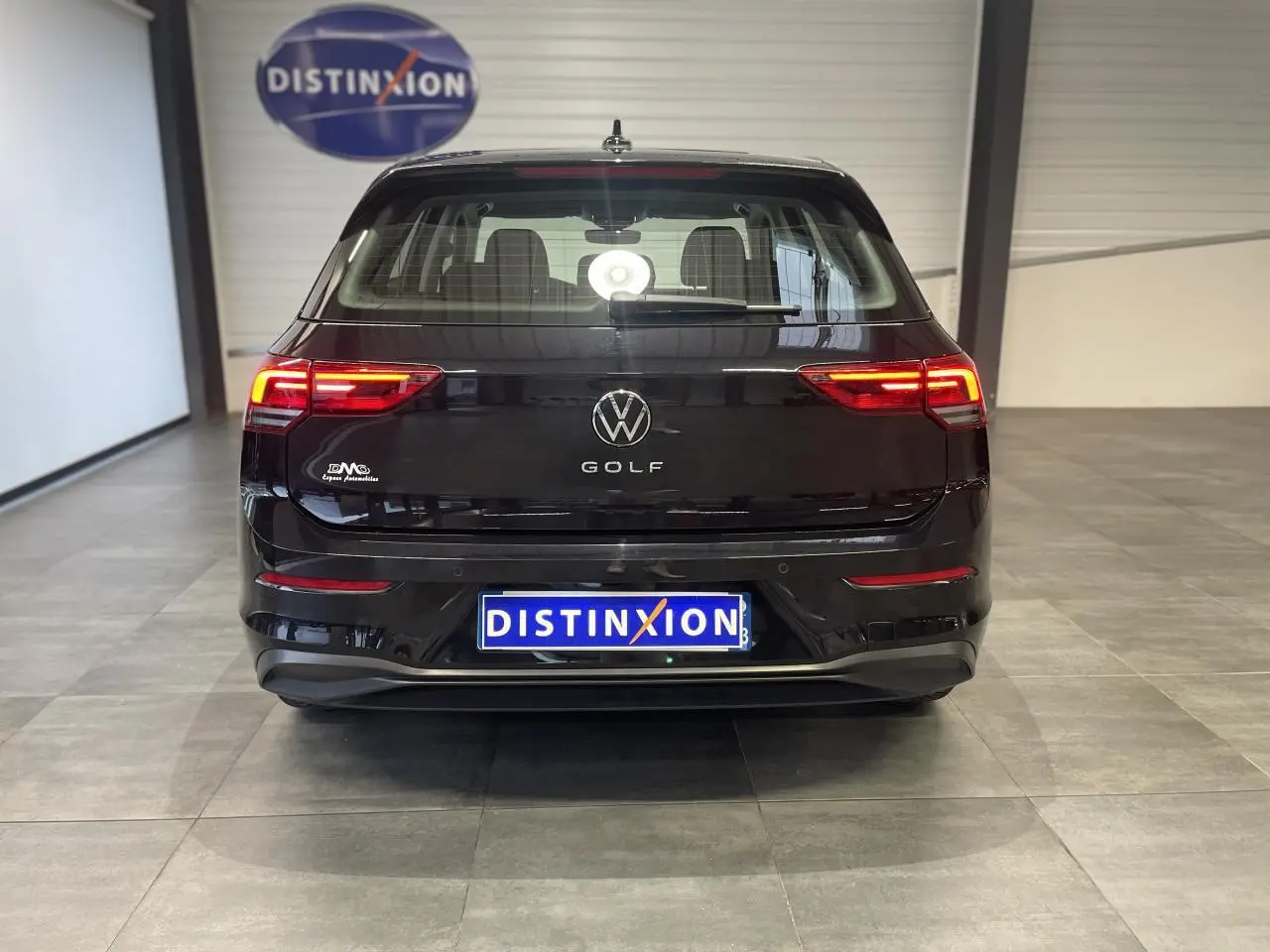 Vue arrière d'une Volkswagen Golf 1.5 eTSI noire 2024 avec feux LED allumés dans un showroom.