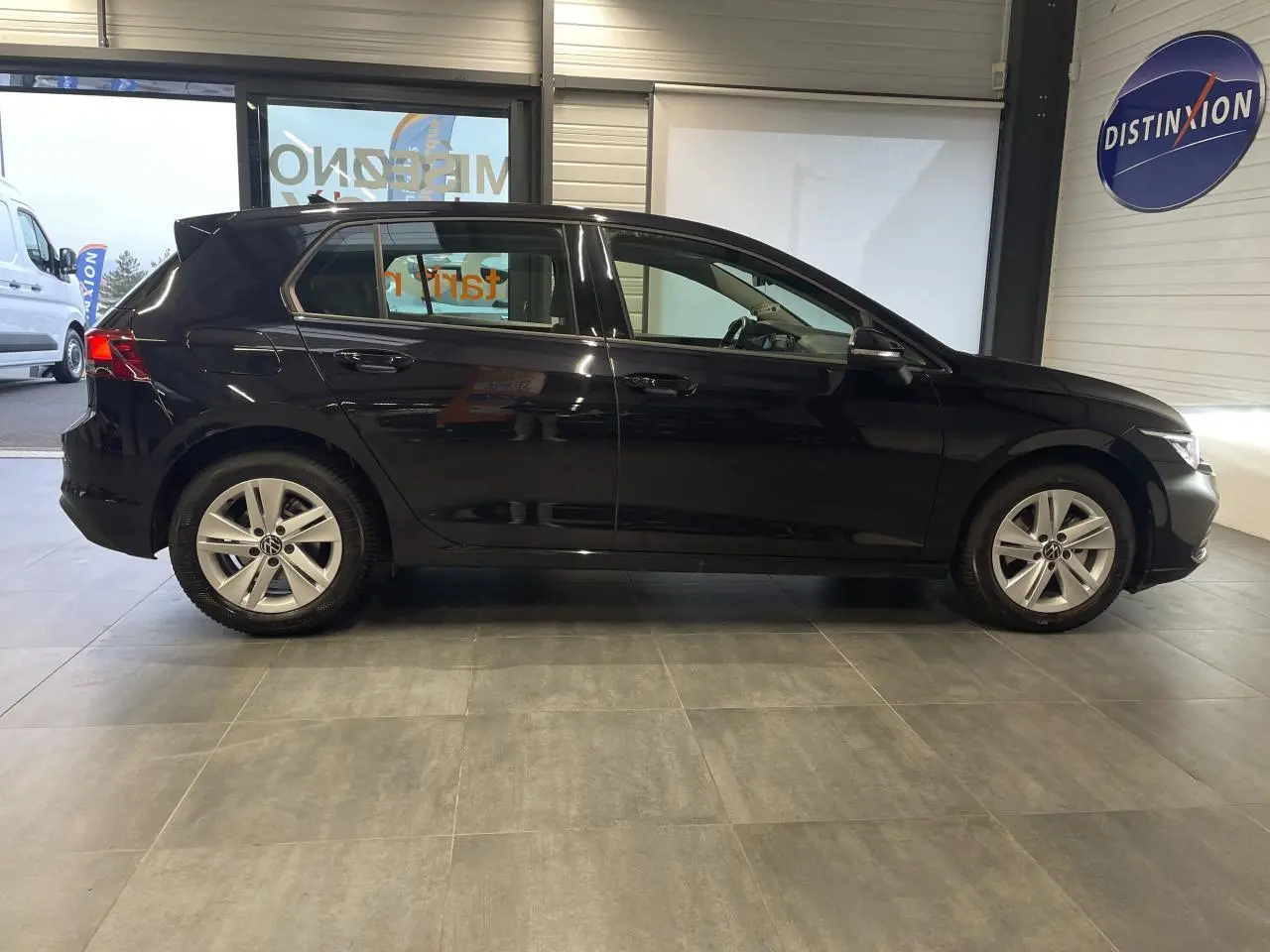 Profil latéral droit d'une Volkswagen Golf noire 2024, avec jantes alliage 17 pouces et poignées couleur carrosserie.