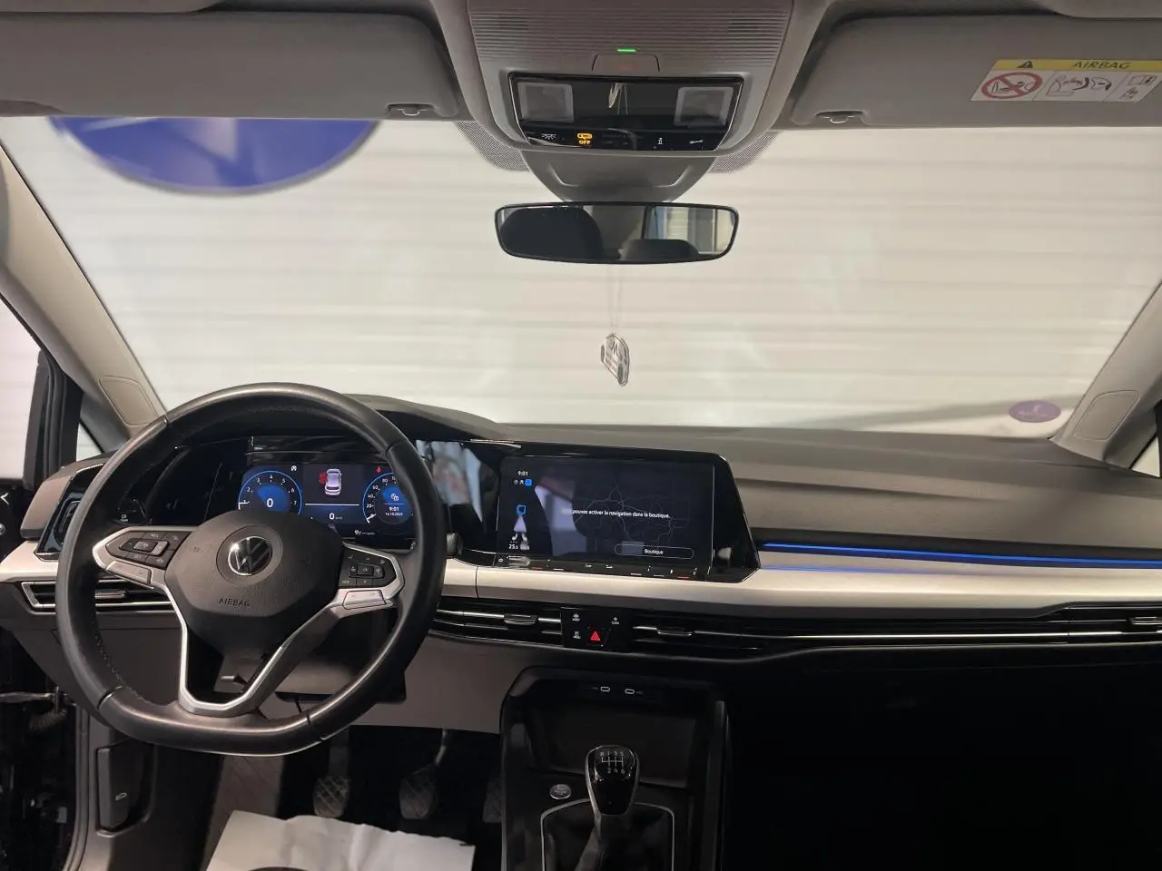 Intérieur noir de la Volkswagen Golf 1.5 eTSI 2024, vue frontale du tableau de bord avec volant et écran tactile.