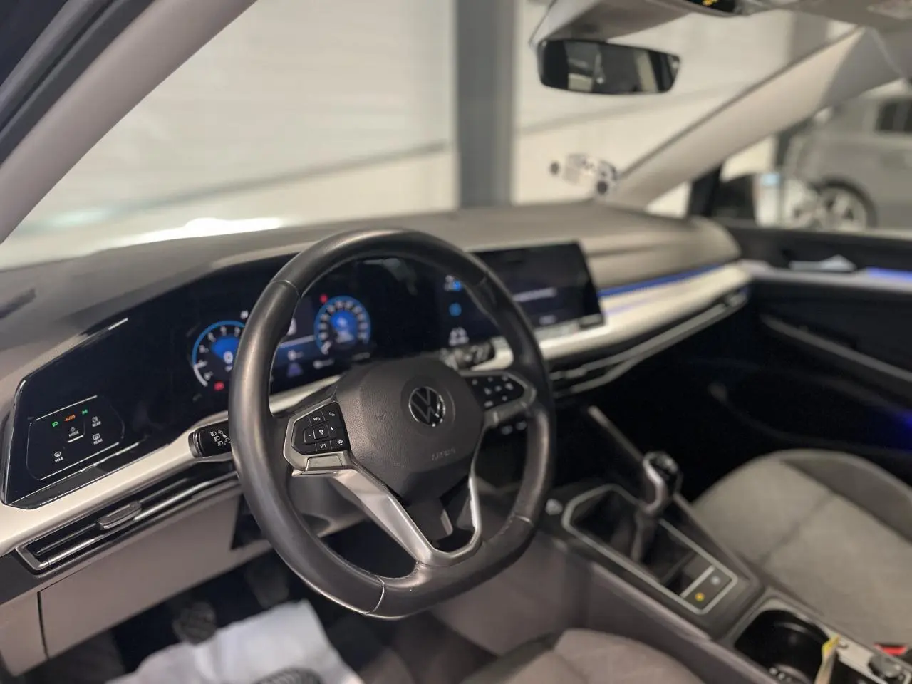 Intérieur de la Volkswagen Golf 1.5 eTSI 2024, vue du poste de conduite avec volant cuir et tableau de bord digital.