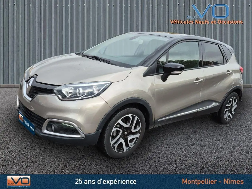 Renault Captur gris en 3/4 avant droit, jantes alliage 17 pouces et vitres surteintées visibles sur parking.