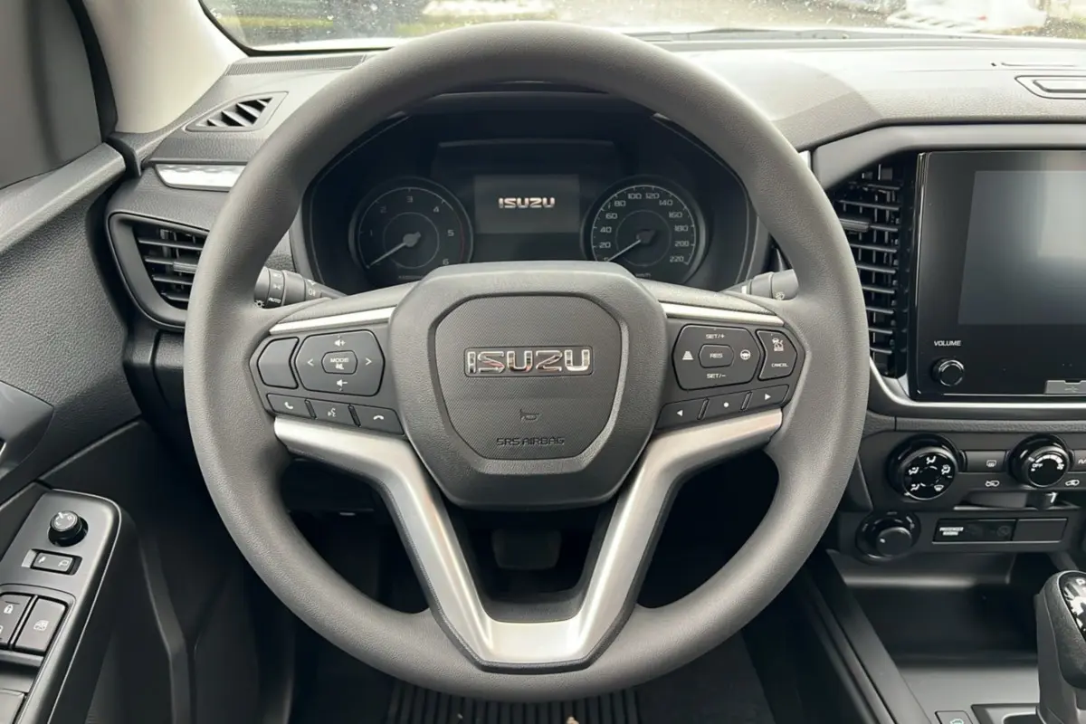 Vue intérieure centrée sur le volant multifonctions gris de l'Isuzu D-MAX 2026 avec tableau de bord et écran tactile.