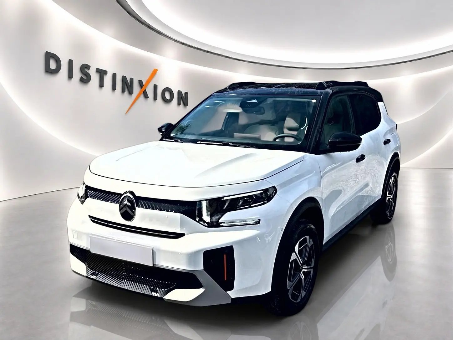 Citroën C3 Aircross blanc vue 3/4 avant droit avec toit noir et jantes alu dans showroom lumineux.