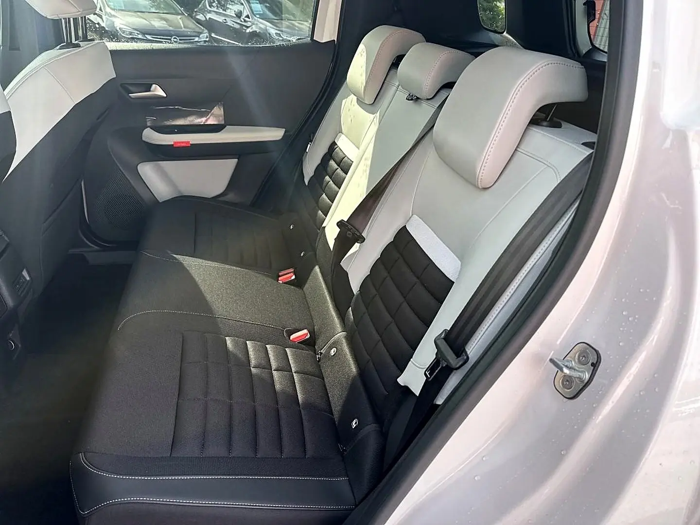 Vue côté droit sur l'intérieur arrière du Citroën C3 Aircross blanc, sièges bicolores noir et beige avec appuie-têtes.