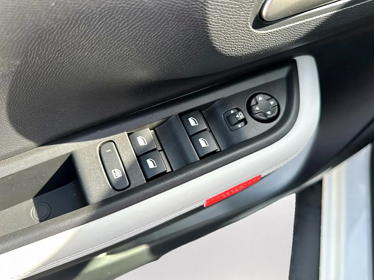 Gros plan sur la commande des vitres côté gauche de la porte avant d'une Citroën C3 Aircross blanche, avec bouton de réglage des rétroviseurs.