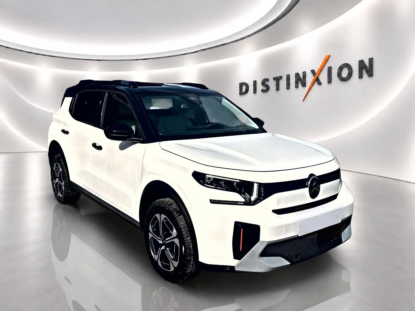 Citroën C3 Aircross blanc vue 3/4 avant droit avec toit noir et jantes alu dans showroom lumineux.