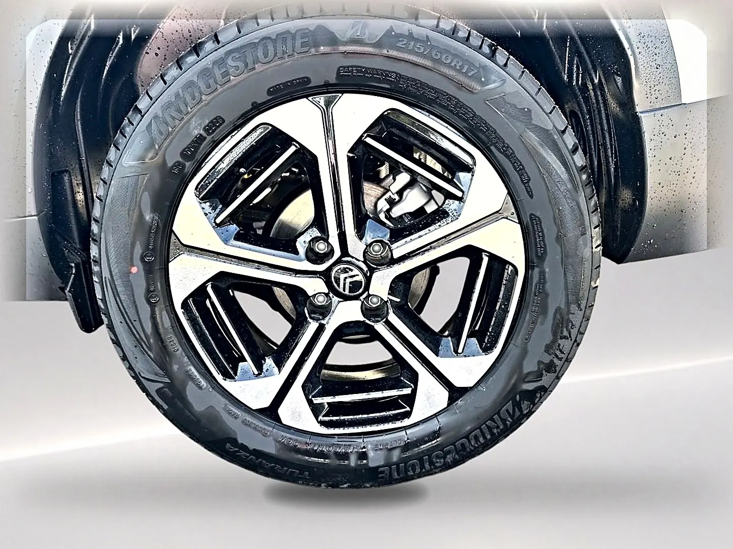 Gros plan sur la jante alu noire et argentée d'une Citroën C3 Aircross blanche, vue côté roue avant droite.