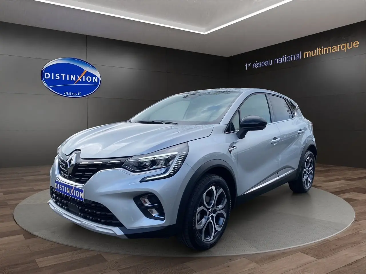 Renault Captur TCE 90 TECHNO gris Highland en 3/4 avant droit, avec jantes alliage et calandre noire brillante.