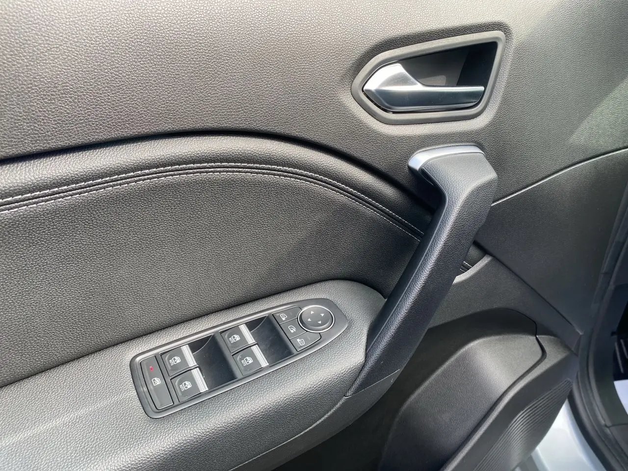 Gros plan sur la porte avant gauche intérieure noire du Renault Captur TCE 90 Techno 2024 avec commandes de vitres électriques.