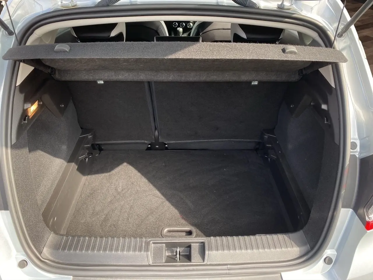 Coffre ouvert du Renault Captur TCe 90 Techno gris Highland, montrant un espace de rangement propre et spacieux.