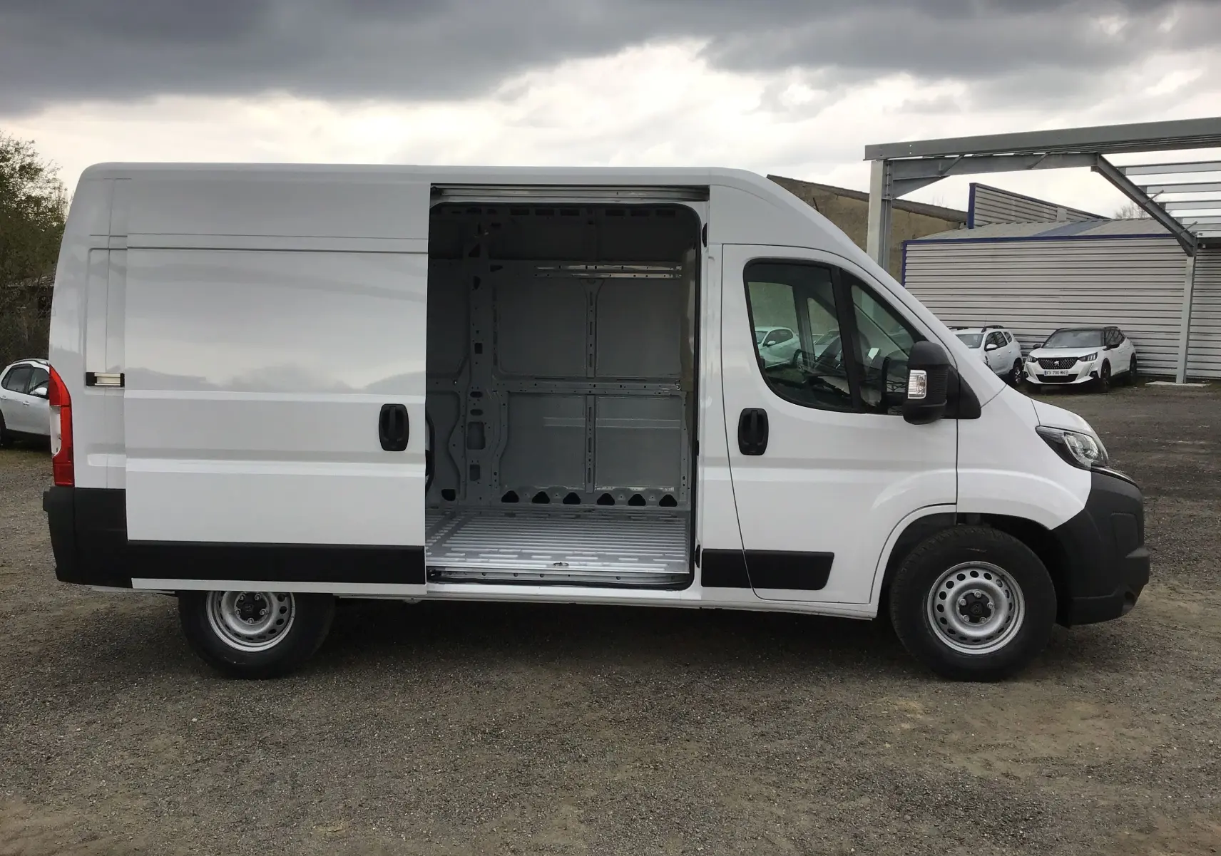 Peugeot Boxer Fourgon blanc vu de profil côté droit, porte coulissante ouverte montrant l'espace de chargement vide.